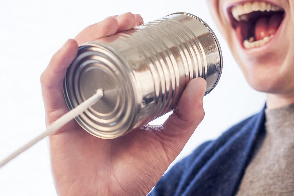 Person talking into a old timey can "phone" representing getting your creative marketing message out there. Fix and form strategic branding agency, Denver, Colorado
